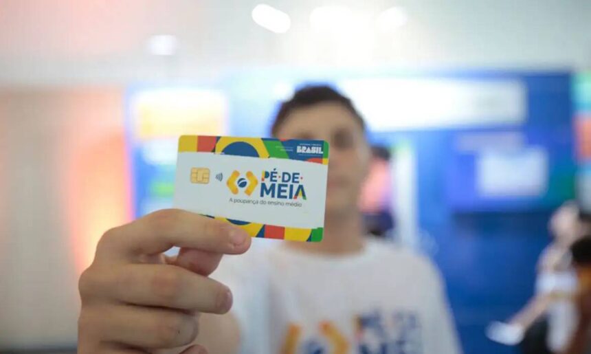 Pessoa segurando um cartão Pé de Meia, iniciativa para poupança estudantil no Brasil, destacando o chip e design colorido.