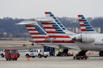 Aviões estacionados no aeroporto, equipe de solo realizando manutenção, veículos de serviço ao redor.