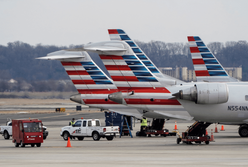 Aviões estacionados no aeroporto, equipe de solo realizando manutenção, veículos de serviço ao redor.