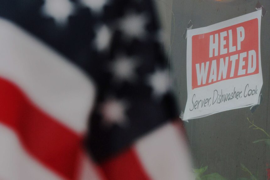 Cartaz de Help Wanted em janela, buscando por garçom, lavador de pratos e cozinheiro. Bandeira americana em destaque.