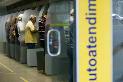 Clientes utilizam caixas eletrônicos em um banco para transações financeiras, destacando o serviço de autoatendimento.