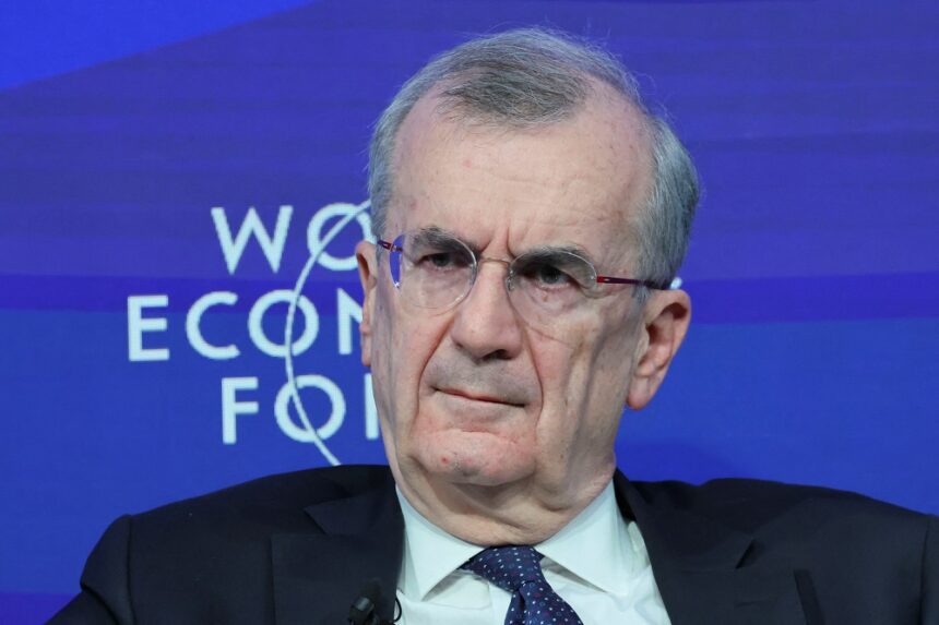 Homem de terno e gravata azul participa de evento com fundo do Fórum Econômico Mundial, ouvindo atentamente.