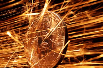 Moeda de bitcoin dourada cercada por faíscas brilhantes, simbolizando transações dinâmicas no mercado de criptomoedas.