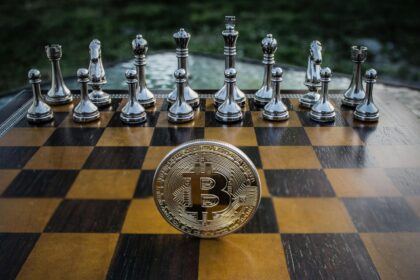 Peças metálicas de xadrez e uma moeda de Bitcoin sobre um tabuleiro, simbolizando a estratégia no investimento em criptomoedas.