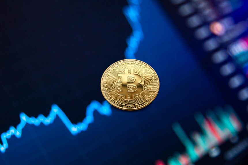 Moeda de Bitcoin destacada em frente a um gráfico de mercado de ações digital, ilustrando flutuações de criptomoedas.