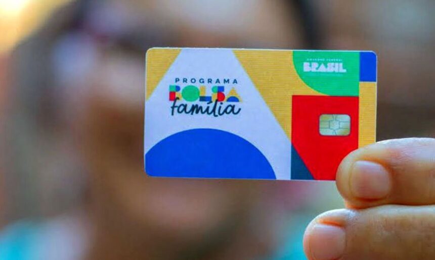 Cartão do Programa Bolsa Família, colorido, sendo segurado por uma mão. Benefício social do governo brasileiro.