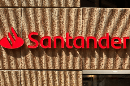 Fachada de agência Santander com logotipo em vermelho destacado sobre parede texturizada, ressaltando a presença do banco.