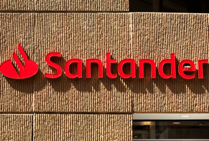 Fachada de agência Santander com logotipo em vermelho destacado sobre parede texturizada, ressaltando a presença do banco.