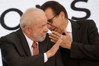 Dois homens em trajes formais interagem em uma conversa privada, conferindo um tom de confidencialidade ao momento.