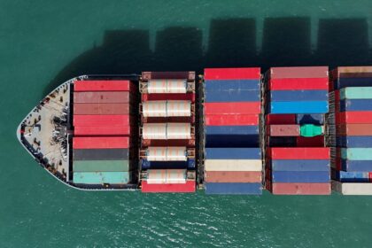 Navio de carga transportando contêineres coloridos em mar aberto, visto de cima. Logística marítima e comércio global.