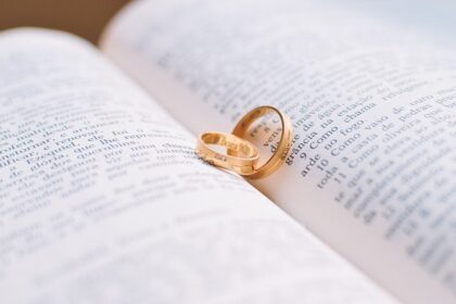 Alianças de casamento douradas repousam sobre as páginas de um livro aberto, simbolizando amor e compromisso duradouro.
