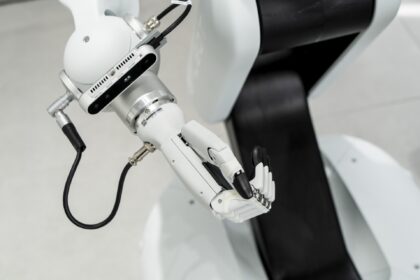 Braço robótico branco em ação com estrutura articulada e sensores avançados, destacando tecnologia de automação industrial.