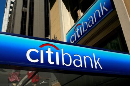 Fachada de agência do Citibank em área urbana, destacando logotipo azul. Edifício com arquitetura moderna ao fundo.