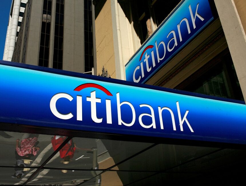 Fachada de agência do Citibank em área urbana, destacando logotipo azul. Edifício com arquitetura moderna ao fundo.