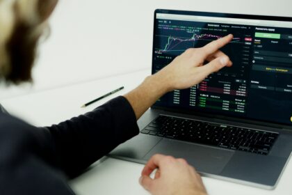 Pessoa analisando gráficos e dados de trading em laptop, com foco na estratégia de investimento e mercado financeiro.