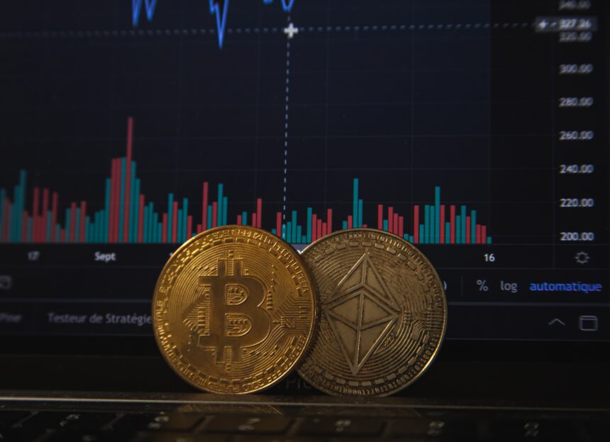 Moedas de Bitcoin e Ethereum em frente a gráfico de ações em tela, ilustrando o mercado de criptomoedas e suas flutuações.