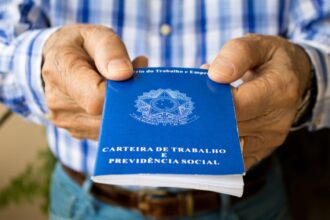 Pessoa segurando uma Carteira de Trabalho azul, importante documento para registros de emprego no Brasil.