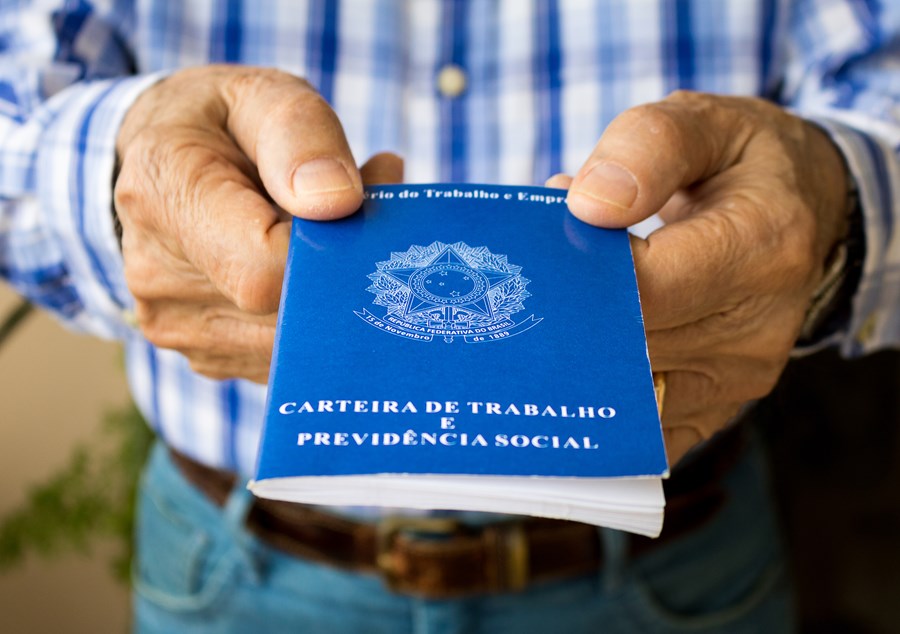Pessoa segurando uma Carteira de Trabalho azul, importante documento para registros de emprego no Brasil.