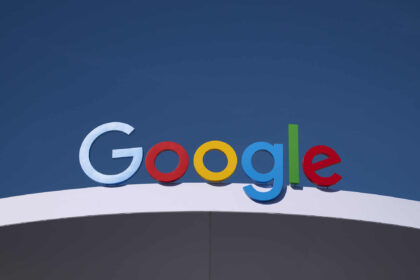 Logo colorido da Google em uma fachada contra um céu azul, representando tecnologia e inovação digital.