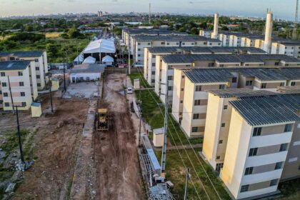 Complexo habitacional em construção com prédios residenciais e tenda ao fundo, evidenciando desenvolvimento urbano.
