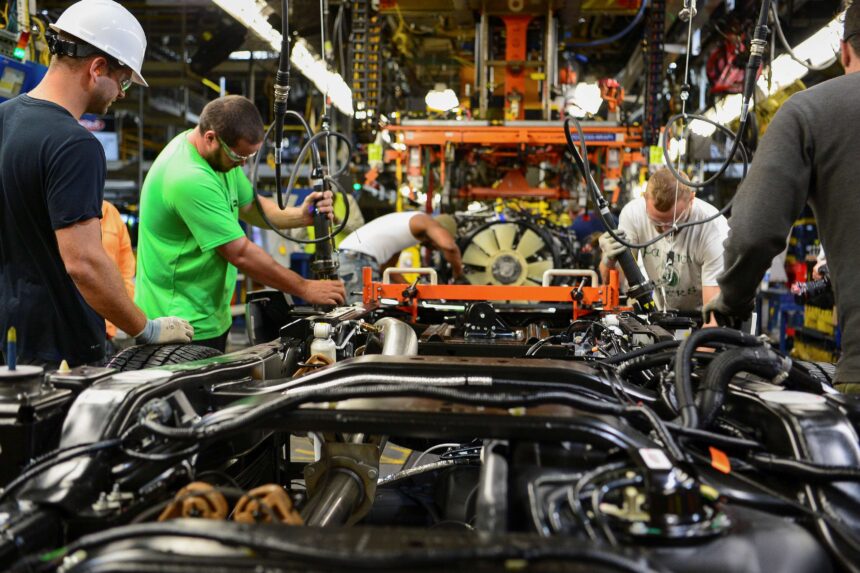 Trabalhadores montam veículos em linha de produção automotiva, destacando infraestrutura industrial e tecnologia de fabricação.