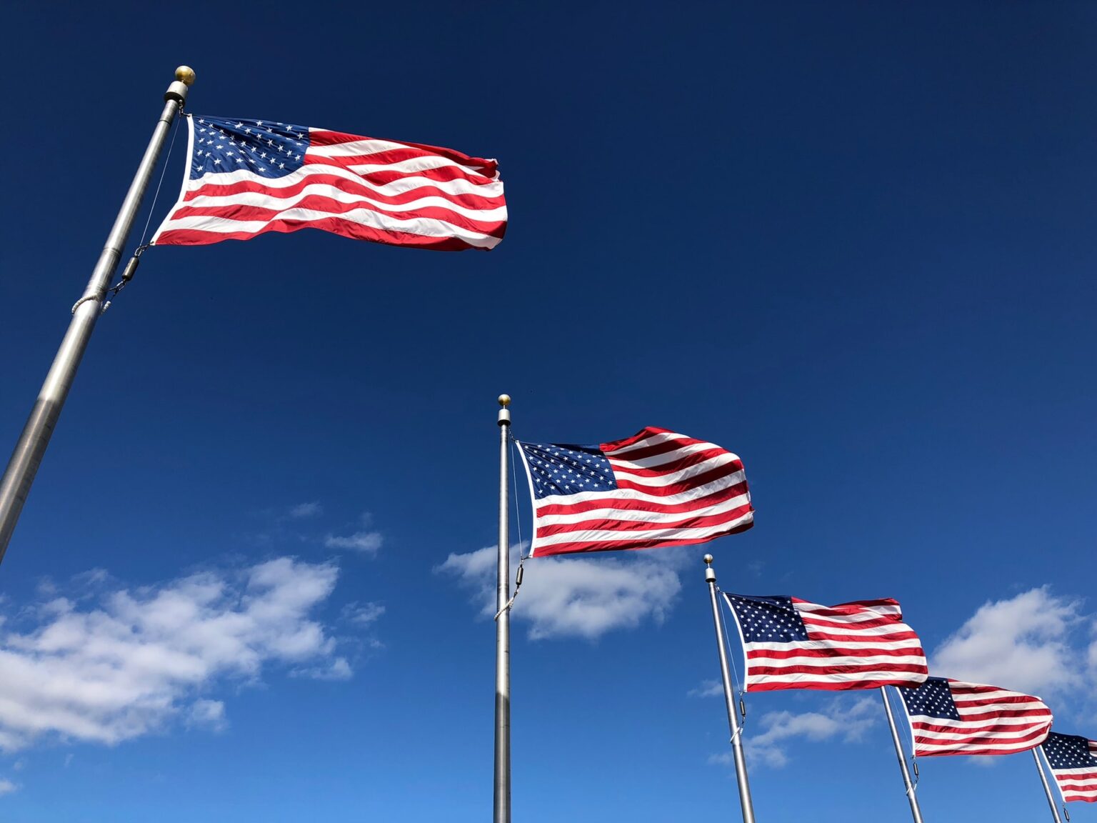 Bandeiras dos Estados Unidos tremulam contra o céu azul, simbolizando patriotismo e orgulho americano.