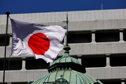 Bandeira do Japão tremula em frente a um prédio moderno, destacando arquiteura e simbolismo nacional.