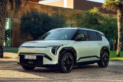 SUV elétrico moderno estacionado em ambiente ao ar livre, rodeado por árvores e edifícios contemporâneos.