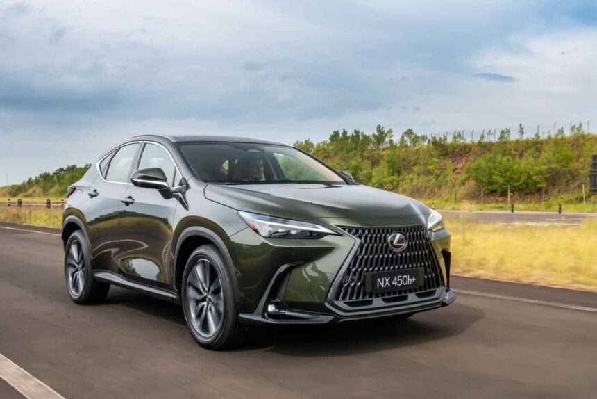 SUV Lexus NX 450h+ verde em alta velocidade em estrada com vegetação ao fundo, destacando design moderno e elegante.
