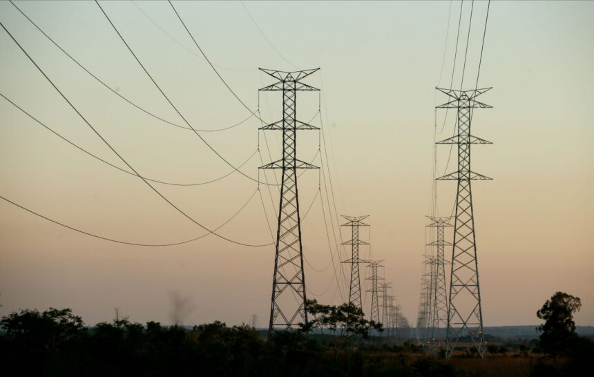 Torres de transmissão de energia ao pôr do sol, destacando infraestrutura elétrica em paisagem rural.