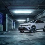 SUV branco estacionado em garagem urbana iluminada, destacando design moderno e linhas esportivas em ambiente industrial.