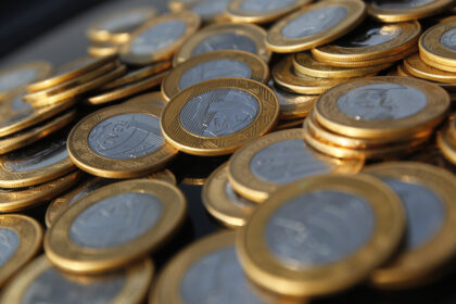 Moedas de real espalhadas, destacando detalhes dourados e prateados, simbolizando economia e finanças no Brasil.