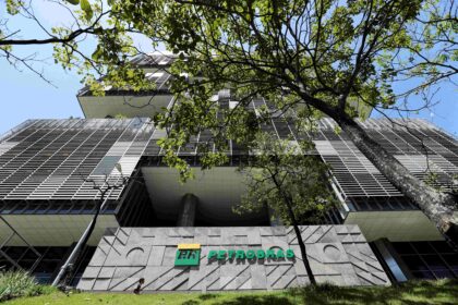 Prédio da sede da Petrobras com fachada moderna, cercado por árvores, destacando-se em um dia de céu claro e azul.