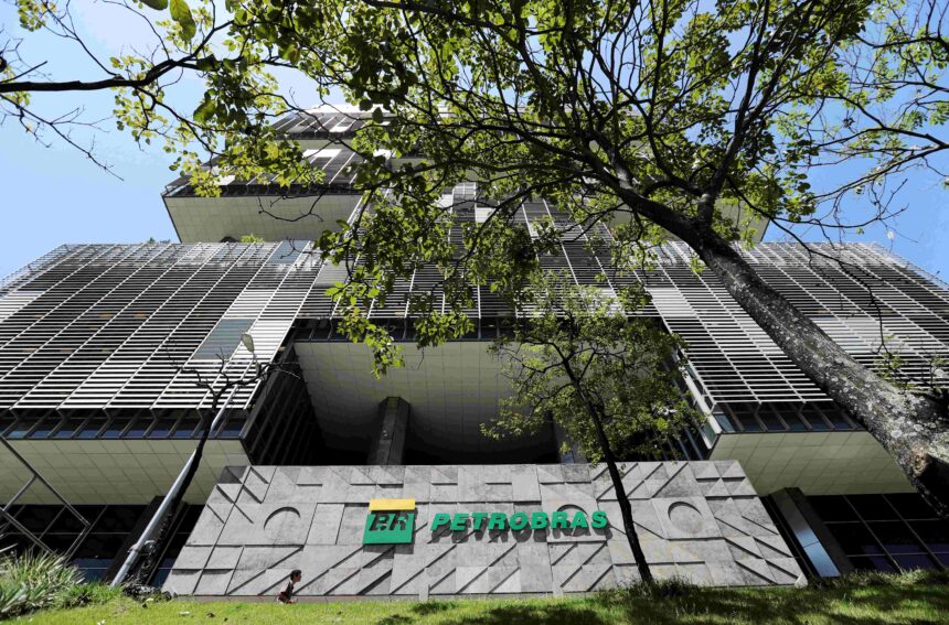 Prédio da sede da Petrobras com fachada moderna, cercado por árvores, destacando-se em um dia de céu claro e azul.