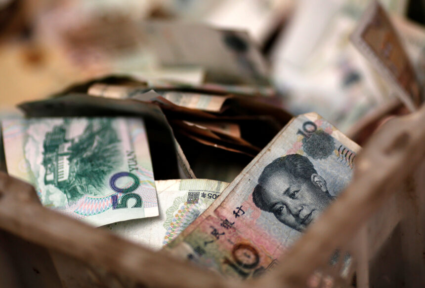 Notas de yuan espalhadas em uma bandeja, destacando uma cédula de 50 yuan.