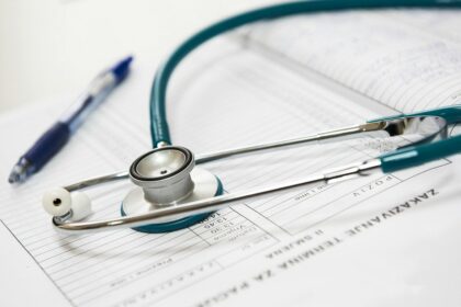Estetoscópio sobre documento médico com caneta azul ao lado, simbolizando cuidados de saúde e registros clínicos.