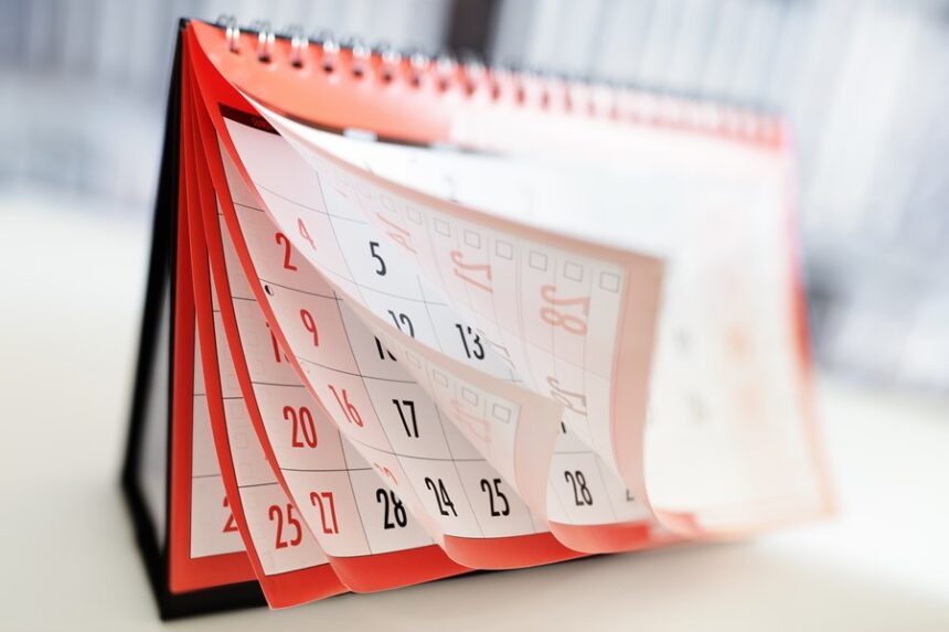 Calendário de mesa com páginas virando rapidamente, destacando passagem dos dias e a organização de compromissos mensais.