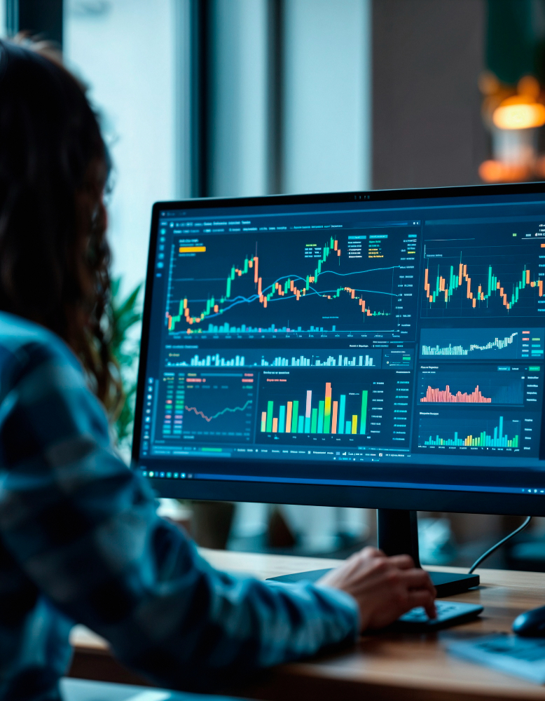 Pessoa analisando gráficos de ações em monitor, destacando tendências e dados financeiros em ambiente corporativo moderno.