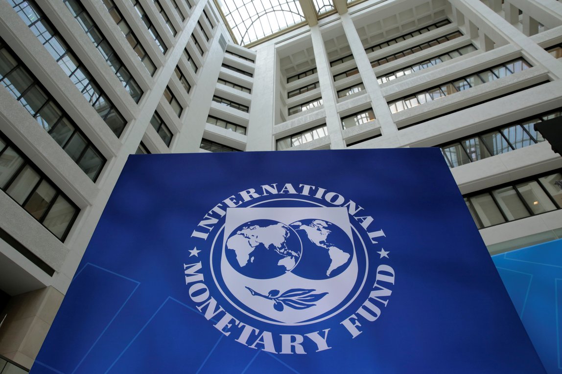 Sede do FMI com logotipo no centro, destacando-se no átrio arquitetônico imponente do edifício internacional.