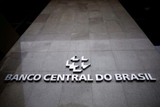 Fachada do Banco Central do Brasil em Brasília, destacando o logotipo e letras em metal brilhante sobre superfície de pedra.