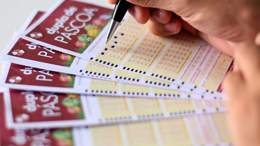Pessoa marca números em bilhetes da Dupla de Páscoa, destacando a expectativa de participar do sorteio especial.