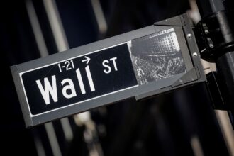 Placa de rua de Wall Street em destaque, símbolo do centro financeiro de Nova York e dos mercados globais.