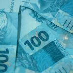 Notas de 100 reais brasileiras empilhadas, destacando detalhes de segurança e design. Ideal para temas sobre economia e finanças.