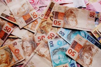 Notas de reais brasileiras de diferentes valores espalhadas, destacando as cédulas de 50 e 100 reais.