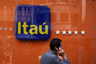 Homem caminha ao telefone em frente a uma agência do Itaú, destacando logo do banco e fachada laranja com estrelas.