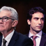 Dois homens de terno, um mais velho usando óculos, outro mais novo, aparecem em um contexto sério ou formal.