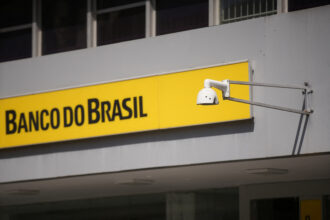 Fachada do Banco do Brasil com câmera de segurança moderna; imagem destaca segurança bancária e proteção de dados.