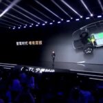 Palco com apresentação sobre tecnologia de baterias automotivas; destaque para imagem técnica projetada em tela grande.