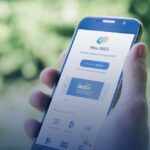 Pessoa segura um smartphone com a tela aberta no aplicativo Meu INSS, oferecendo acesso a serviços do INSS online.