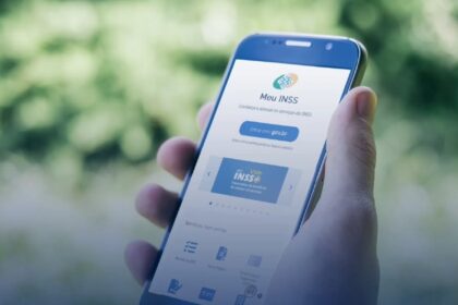 Pessoa segura um smartphone com a tela aberta no aplicativo Meu INSS, oferecendo acesso a serviços do INSS online.